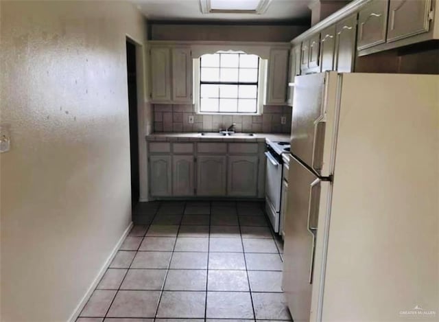 kitchen with decorative backsplash, light tile patterned floors, white refrigerator, and stainless steel stove