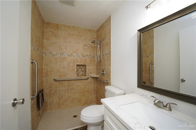 bathroom with vanity, toilet, and tiled shower