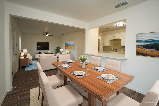 dining room with ceiling fan, sink, and dark hardwood / wood-style floors