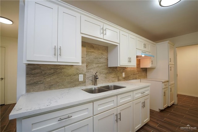 kitchen featuring white cabinetry, sink, light stone countertops, dark wood-type flooring, and tasteful backsplash