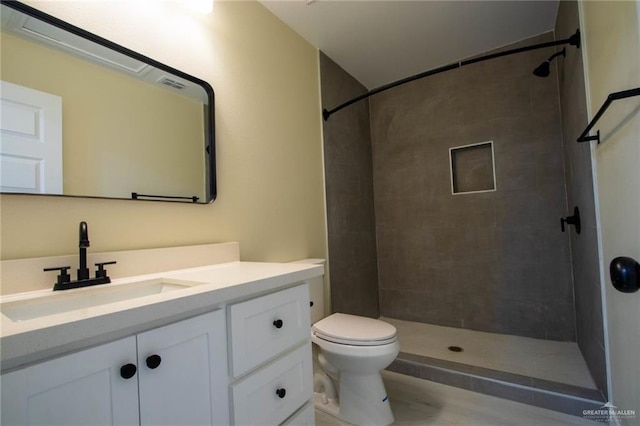 bathroom with vanity, toilet, and a tile shower