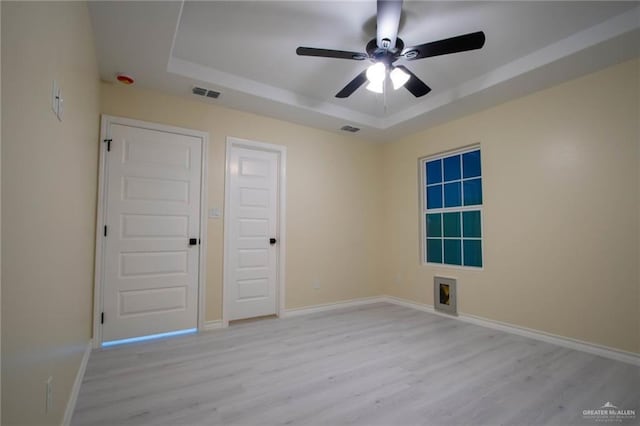 unfurnished bedroom featuring ceiling fan, light hardwood / wood-style flooring, and a raised ceiling