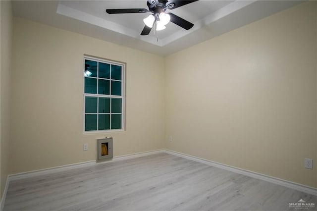 empty room featuring ceiling fan, a raised ceiling, and light hardwood / wood-style flooring