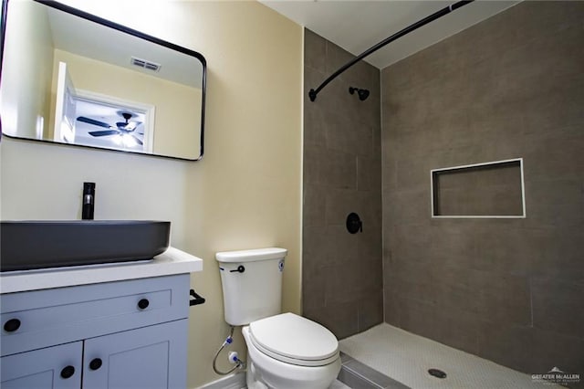 bathroom with vanity, toilet, and tiled shower