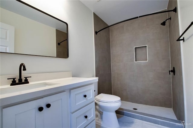 bathroom with vanity, a tile shower, and toilet