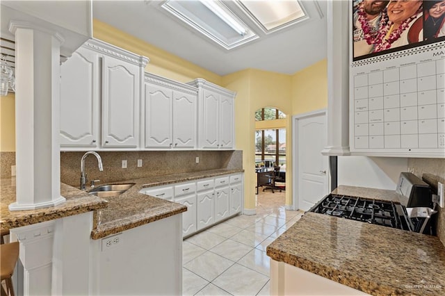 1800 E 24th St, Mission, TX 78574 - kitchen with a peninsula, light tile patterned flooring, white cabinetry, a sink, and backsplash