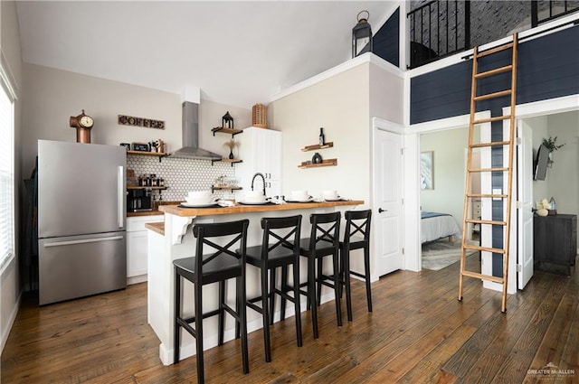 1053 Johnson Rd, Santa Fe, TX 77617 - kitchen with freestanding refrigerator, wall chimney range hood, open shelves, wooden counters, and a kitchen breakfast bar