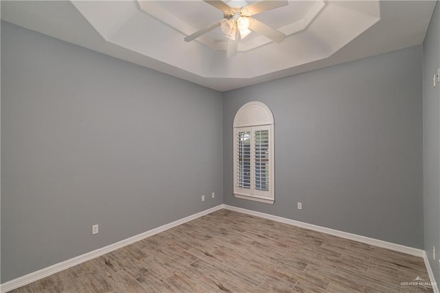 unfurnished room featuring a tray ceiling, ceiling fan, and wood-type flooring