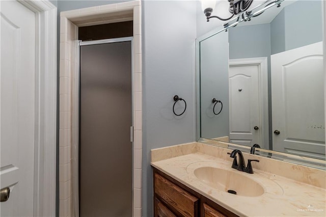 bathroom featuring a shower with door and vanity