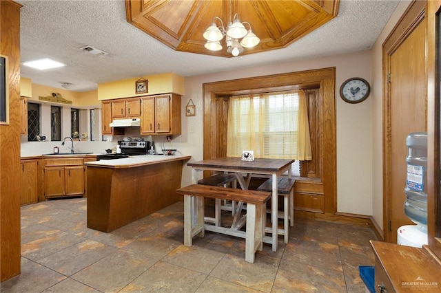 2403 Silver Oak Ave, Mission, TX 78574 - kitchen featuring under cabinet range hood, an inviting chandelier, a sink, brown cabinetry, and stainless steel electric range oven
