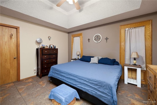 2403 Silver Oak Ave, Mission, TX 78574 - bedroom featuring ceiling fan, stone tile flooring, a tray ceiling, and a textured ceiling