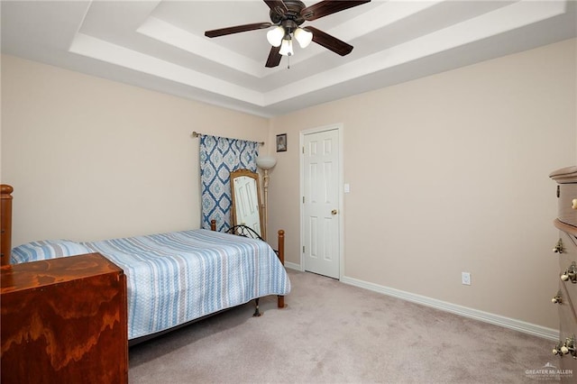 bedroom with light carpet, a tray ceiling, and ceiling fan