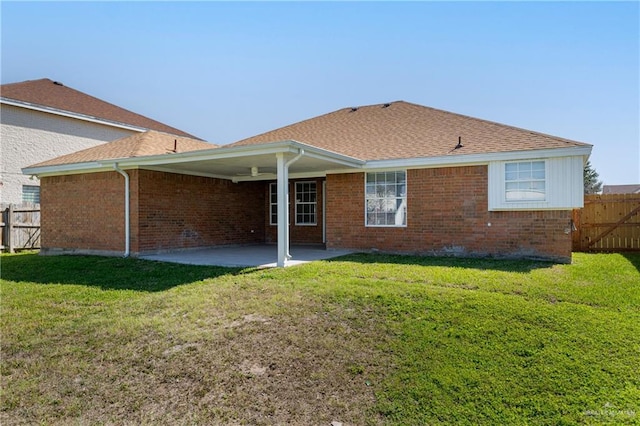 back of property with a shingled roof, a patio, fence, a yard, and brick siding