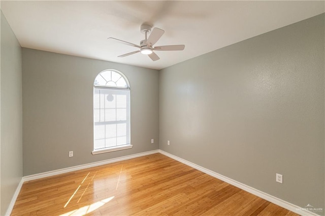 spare room with light wood finished floors, a ceiling fan, and baseboards