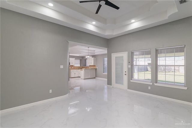 unfurnished living room with baseboards, a raised ceiling, and recessed lighting