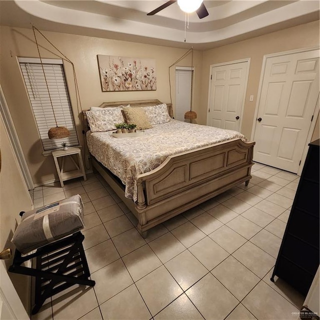 bedroom featuring light tile patterned floors, ceiling fan, and a raised ceiling