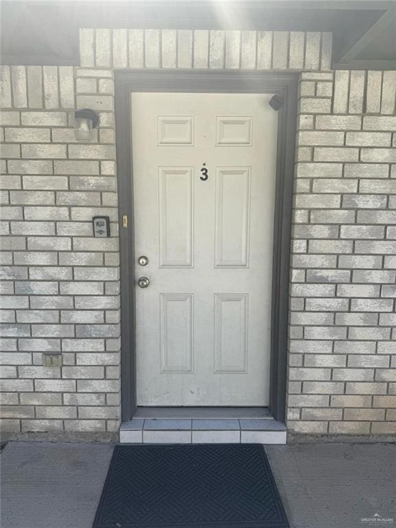 entrance to property featuring roof with shingles