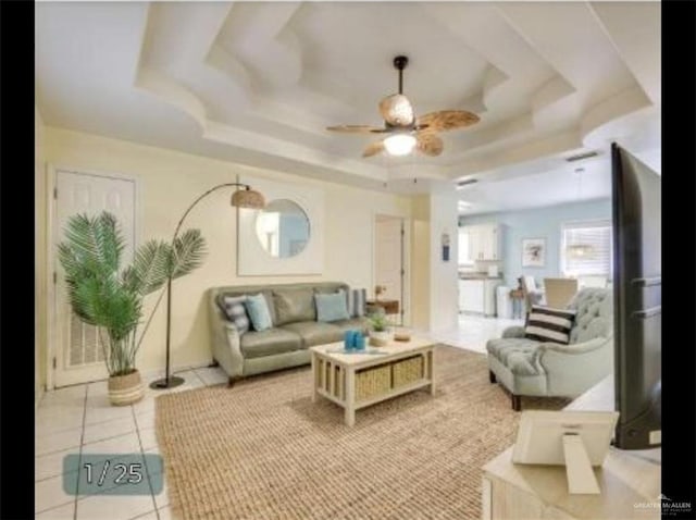 living room featuring a ceiling fan, a tray ceiling, and light tile patterned floors