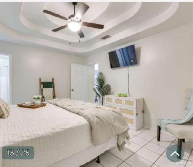 bedroom featuring visible vents, a tray ceiling, a ceiling fan, and light tile patterned flooring