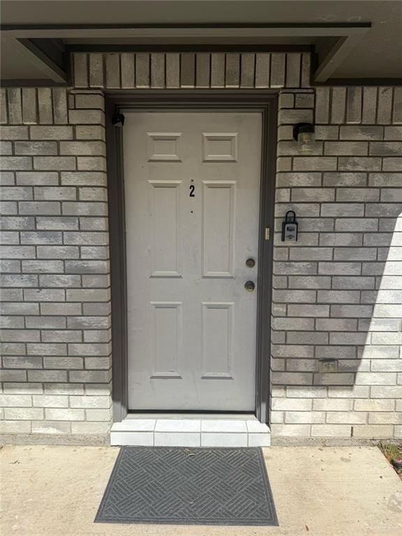 entrance to property featuring brick siding