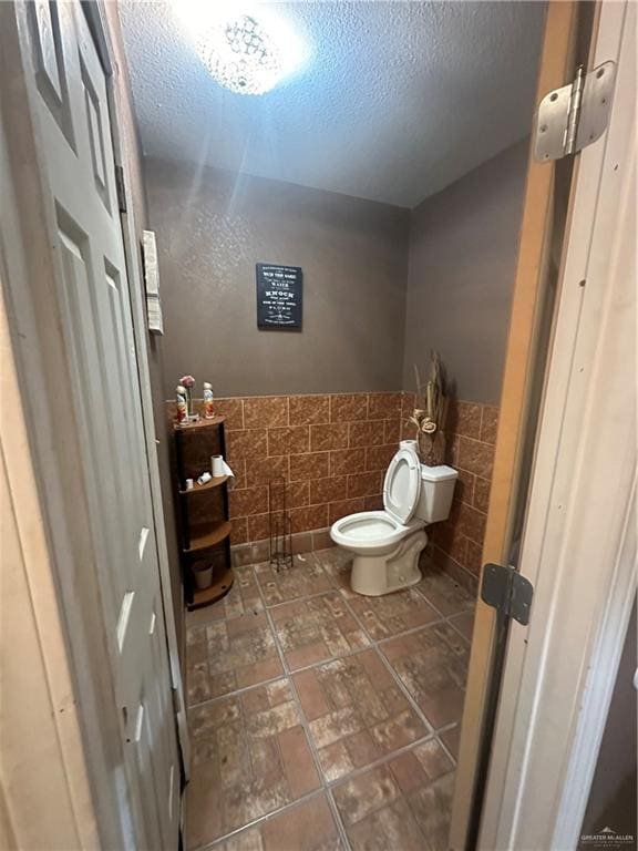 bathroom featuring toilet and tile walls