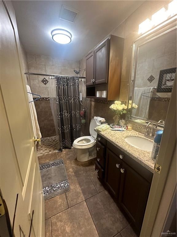 bathroom featuring a shower with shower curtain, tile patterned floors, vanity, and toilet