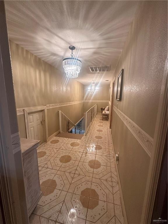 hall with an inviting chandelier and light tile patterned flooring