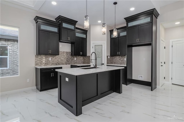 kitchen featuring marble finish floor, a sink, a kitchen island with sink, and recessed lighting