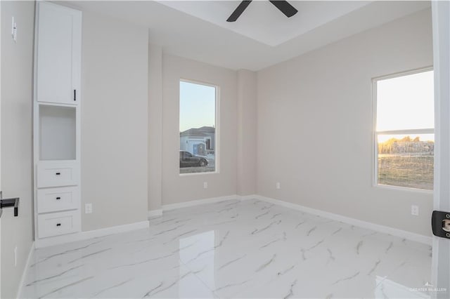 unfurnished bedroom with ceiling fan, marble finish floor, and baseboards