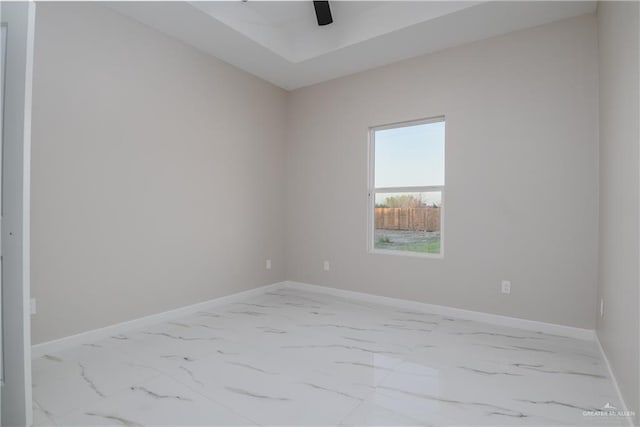 spare room featuring marble finish floor, ceiling fan, and baseboards