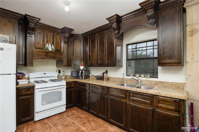 kitchen with light stone counters, dark brown cabinets, white appliances, dark tile patterned floors, and sink