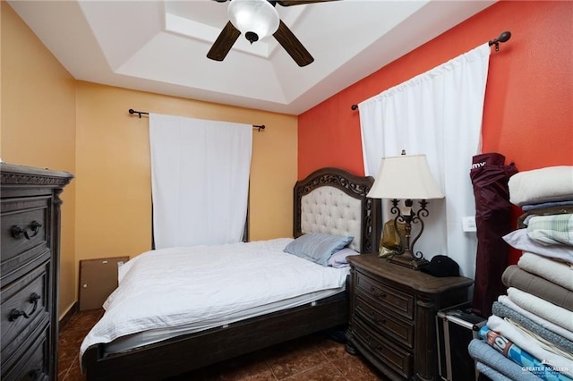 bedroom with a tray ceiling, ceiling fan, and dark tile patterned floors