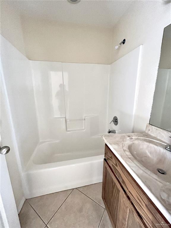 bathroom with tile patterned flooring, vanity, and  shower combination