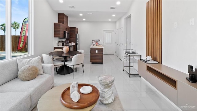 living area with plenty of natural light, visible vents, and marble finish floor