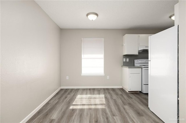 kitchen with white appliances, white cabinetry, a textured ceiling, decorative backsplash, and light wood-type flooring