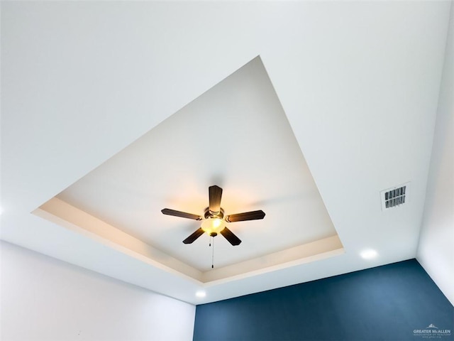 room details featuring ceiling fan and a tray ceiling