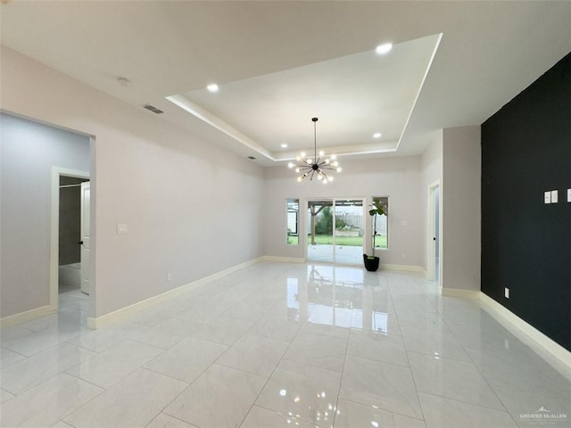 unfurnished room featuring a chandelier and a tray ceiling