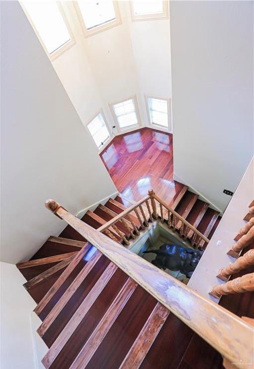 stairway with wood-type flooring, high vaulted ceiling, and plenty of natural light