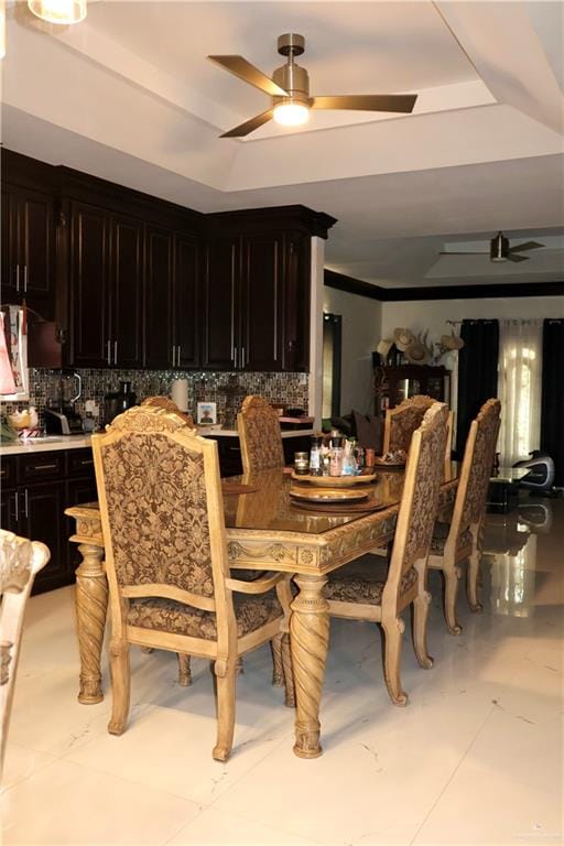 tiled dining space featuring a raised ceiling and ceiling fan