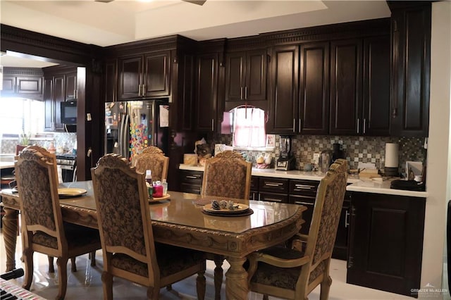 interior space with decorative backsplash, a healthy amount of sunlight, dark brown cabinetry, and stainless steel refrigerator with ice dispenser