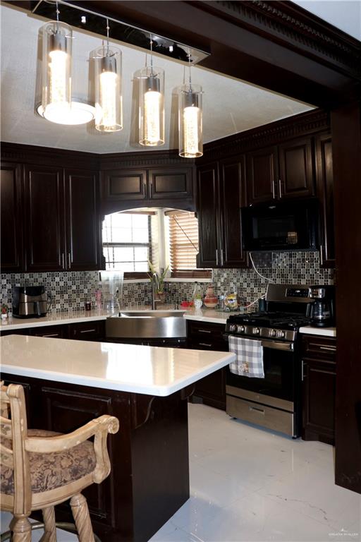 kitchen featuring sink, a kitchen bar, backsplash, and stainless steel stove