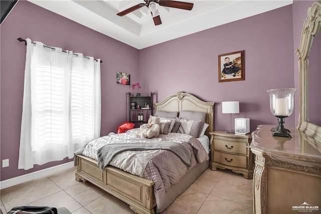 bedroom with multiple windows, light tile patterned floors, a tray ceiling, and ceiling fan