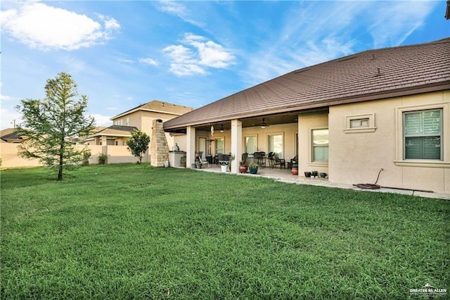 back of property with a yard and a patio area