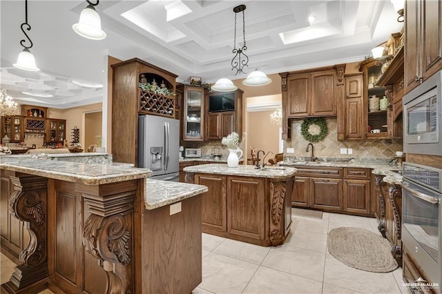 kitchen featuring pendant lighting, stainless steel appliances, kitchen peninsula, and a center island with sink