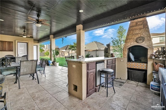 view of patio / terrace featuring an outdoor stone fireplace, area for grilling, an outdoor bar, and ceiling fan