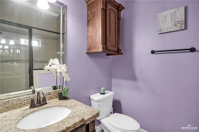 bathroom featuring vanity, walk in shower, and toilet