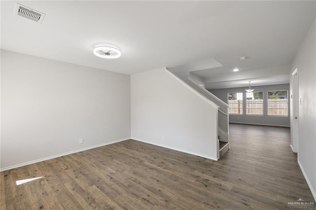 spare room featuring stairway, baseboards, visible vents, and dark wood-type flooring