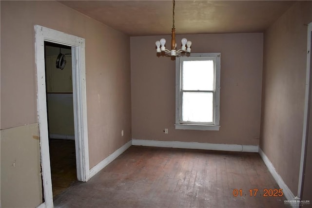 spare room with hardwood / wood-style floors and a notable chandelier