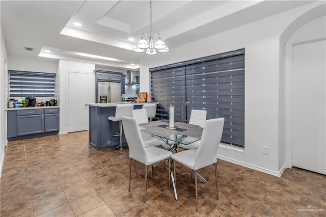 dining room with a notable chandelier and a raised ceiling