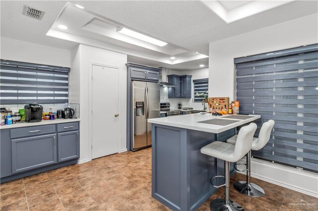 kitchen featuring a tray ceiling, kitchen peninsula, stainless steel appliances, and a kitchen breakfast bar